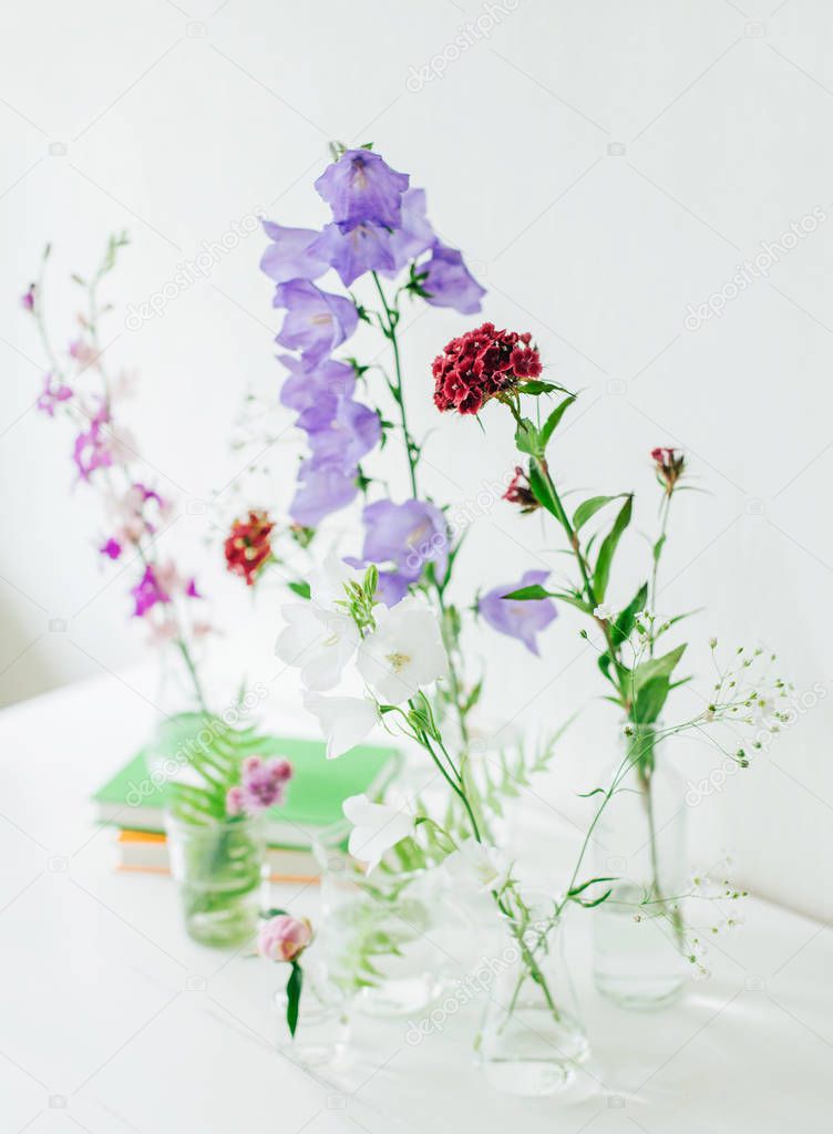 Beautiful composition with perfume samples and flowers on table. Flowers in flasks. Wildflowers. Summer bouquet.