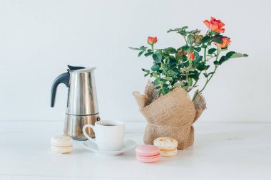 Kahve kupa, kahve pot, macaroons ve kopya alanı ile hafif masaya çiçek