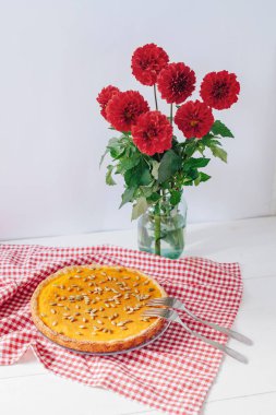 Kabak pasta çatal masada peçete ve kırmızı çiçekler vazoda beyaz tabakta servis
