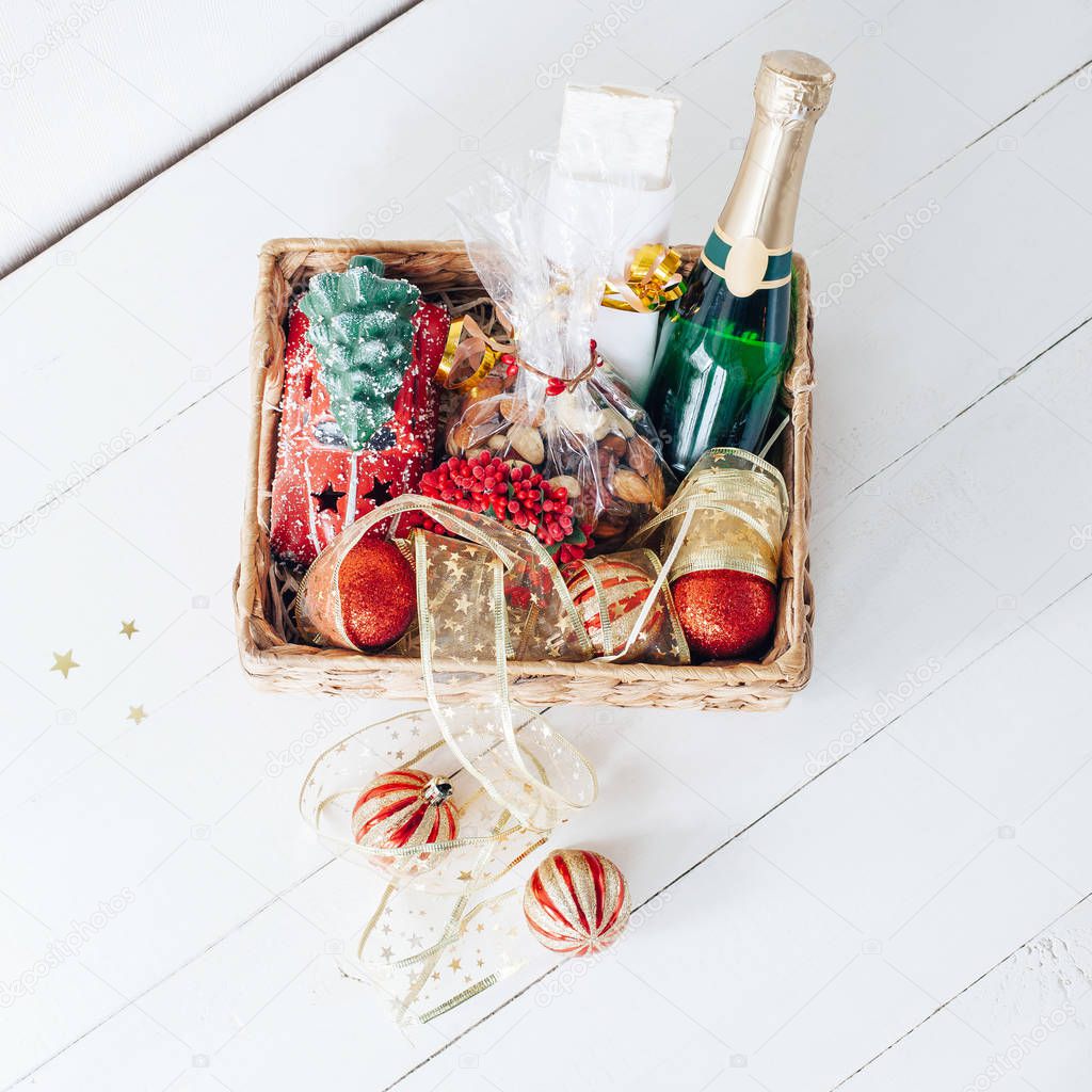 wicker basket of christmas decorations and gifts, nuts and champagne bottle