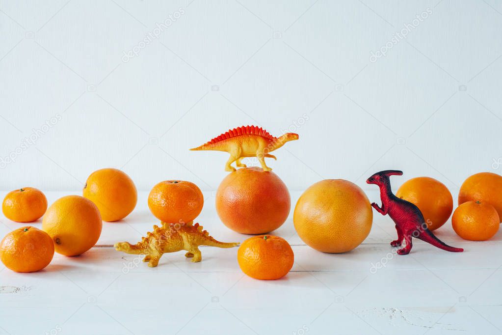 Citrus fruits isolated on white background. Isolated citrus fruits. Grapefruit, mandarin, orange isolated on white background. Dinosaur toys.