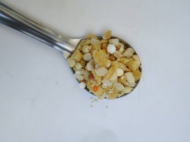 Beyaz arka planda izole edilmiş çelik kaşıkta geleneksel ev yapımı Pongal Ellu Bella karışımı.