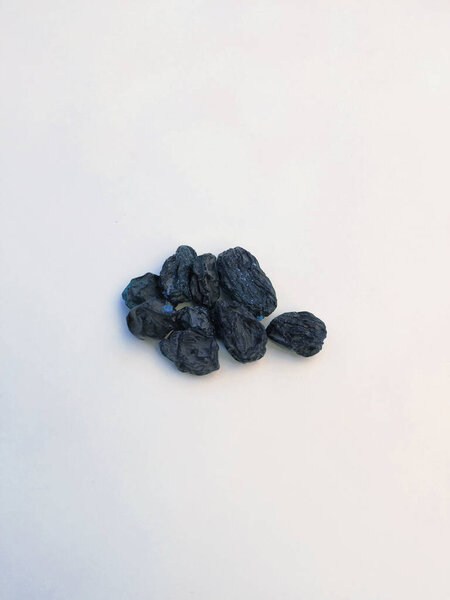 Closeup of dry black raisin fruit isolated in a white background. Heap of blue raisin isolated on white