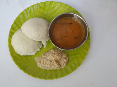 Hint vejetaryen pirinç keki, idli ya da aylak olarak bilinen kahvaltı, sambar ve Chatney ile birlikte beyaz bir arka planda izole edilmiş yeşil bir tabakta servis edilir. Lezzetli Güney Hindistan yemekleri