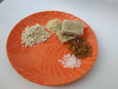 Shri Kshetra Dharmasthala Manjunatha Swamy Prasada 'nın beyaz arka planda izole edilmiş bir tabakta yakın çekimi. Theertha Şişe, Kuru Kishmish, Şeker, Panchakajaya ve Diğer