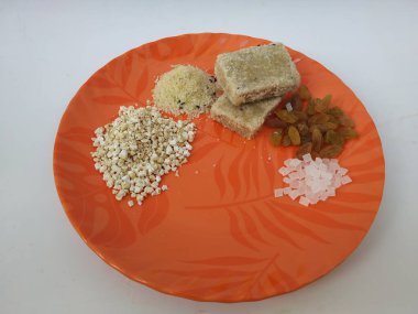 Shri Kshetra Dharmasthala Manjunatha Swamy Prasada 'nın beyaz arka planda izole edilmiş bir tabakta yakın çekimi. Theertha Şişe, Kuru Kishmish, Şeker, Panchakajaya ve Diğer