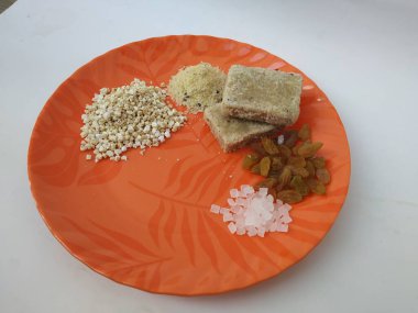 Shri Kshetra Dharmasthala Manjunatha Swamy Prasada 'nın beyaz arka planda izole edilmiş bir tabakta yakın çekimi. Theertha Şişe, Kuru Kishmish, Şeker, Panchakajaya ve Diğer