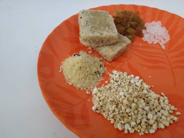 Shri Kshetra Dharmasthala Manjunatha Swamy Prasada 'nın beyaz arka planda izole edilmiş bir tabakta yakın çekimi. Theertha Şişe, Kuru Kishmish, Şeker, Panchakajaya ve Diğer