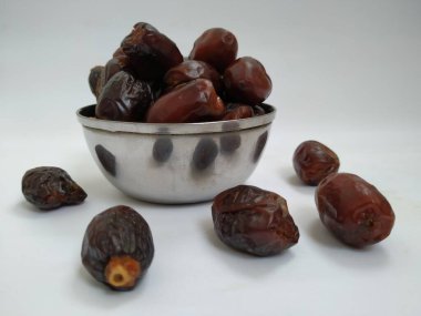 Beyaz arka planda izole edilmiş çelik bir kasede çiğ kahverengi renkli meyvelerin yakın çekimi