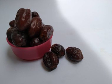 Beyaz arka planda izole edilmiş Plastik bir Pembe Kasede Ham Kuru Tarihler Kahverengi Meyve Yakın plan