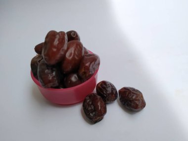 Beyaz arka planda izole edilmiş Plastik bir Pembe Kasede Ham Kuru Tarihler Kahverengi Meyve Yakın plan