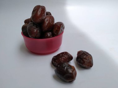 Beyaz arka planda izole edilmiş Plastik bir Pembe Kasede Ham Kuru Tarihler Kahverengi Meyve Yakın plan