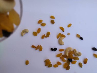 Raisin, Kishmish, Cashew ve Bamond gibi kuru meyvelerden oluşan bir grup şeffaf bir bardağı doldurdu ve izole edilmiş beyaz arka plana dağıttı.