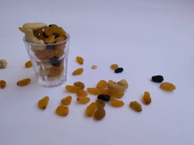 Raisin, Kishmish, Cashew ve Bamond gibi kuru meyvelerden oluşan bir grup şeffaf bir bardağı doldurdu ve izole edilmiş beyaz arka plana dağıttı.