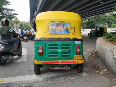 Bangalore, Karnataka / India-Aug 07-2020: Sarı ve Yeşil renkli otomobil Rickshaw 'ın yakın çekimde durduğu yer. Ünlü Kannada Aktörü Yıldız Darshan 'ın Arkaya Resmini Yapıyor