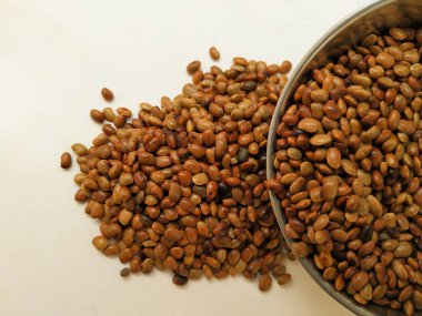 Beyaz zemin üzerinde izole edilmiş Çelik Kupa 'dan Dağılmış At Gram tohumlarının yakın çekimi