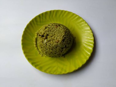 Beyaz arka planda izole edilmiş yeşil renkli bir plaka içinde Çelik Kaşıklı Palak Rice Heap 'in yakın çekimi