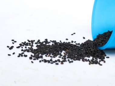 Chia Tohumları ya da Kama Kasturi Tohumlarının Mavi Renkli Plastik Konteynırdan Dağınık Görüntüsü Beyaz Arkaplanda İzole Edildi.