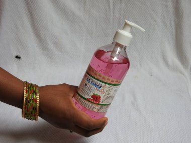 Bangalore, Karnataka / India-Aug 02-2020: Plastik bir şişede bulunan Pembe Renkli Ahududu El Dezenfektanının Kapanışı ve beyaz arka planda elle izole edilmeye uygulanması