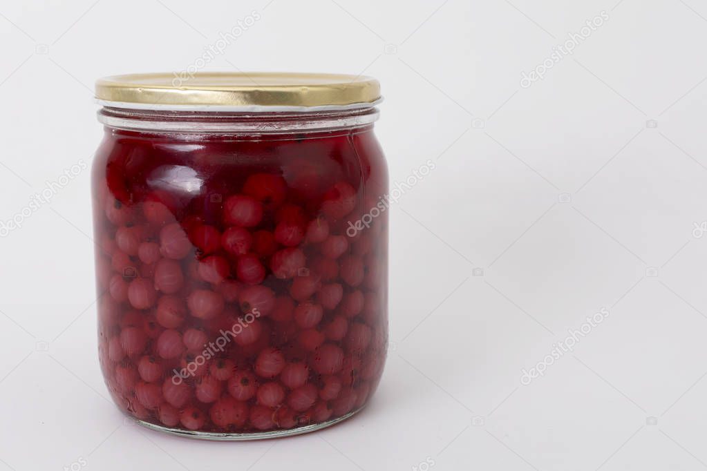 Red currant in a glass jar on a white background.
