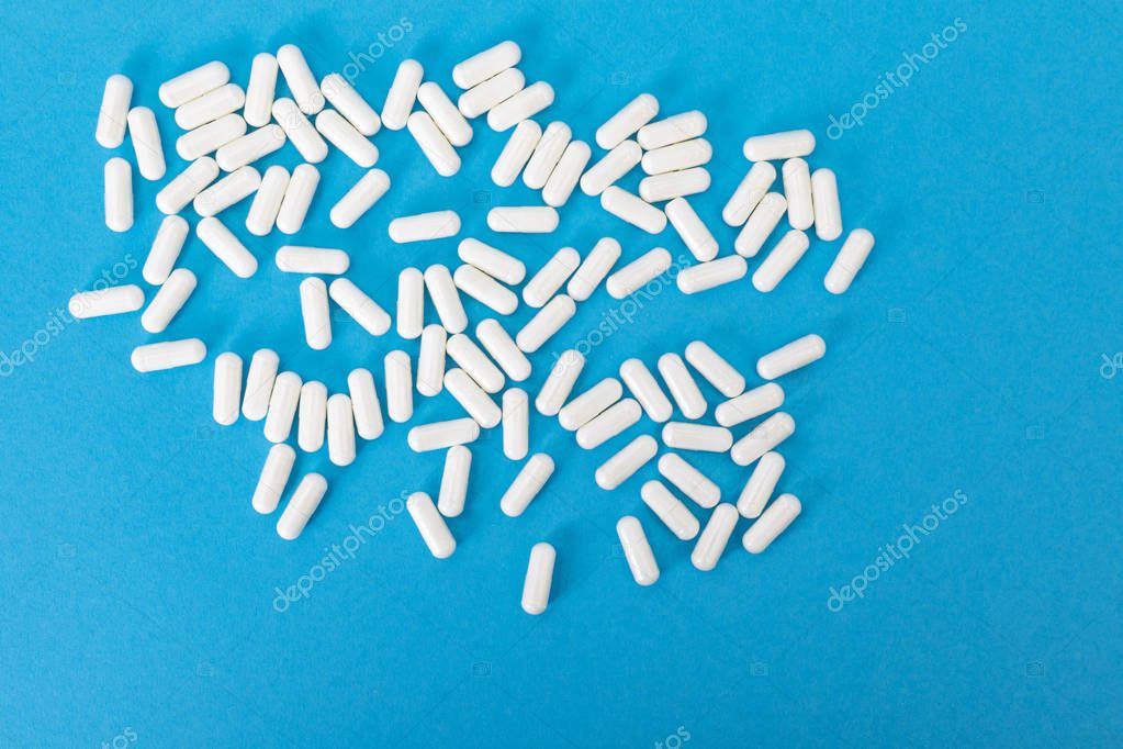 White pills on the blue paper background 