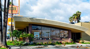 Garden Grove, CA / USA - March 8, 2019: Side view of vintage 1960s Googie style coffee shop with sweeping cantilevered roof and spire. Googie architecture was mid-century, Space Age modern. clipart