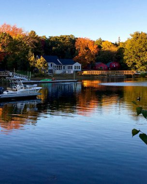 Portsmouth, NH / USA - 10-16-2018: Sagamore Creek 'te öğleden sonra saatlerinde liman, rıhtım, tekne iskelesi, yaprak dökümü ve renkli yansımaların güzel sonbahar su manzarası.