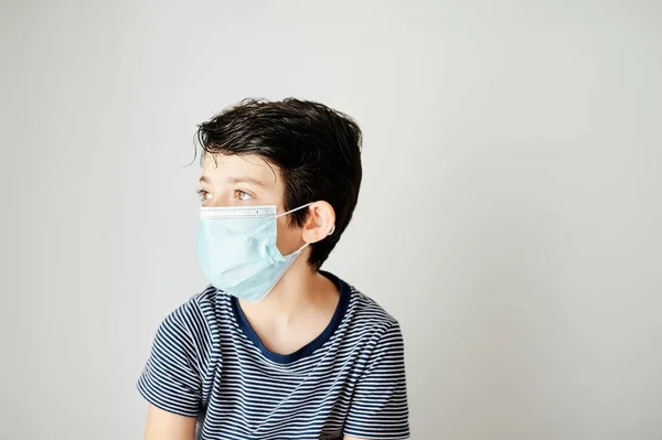 Niño de nueve años que se pone la máscara de protección contra el virus solo . — Foto de Stock