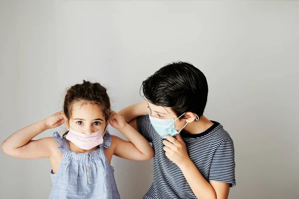 Kardeşler Coronavirus yüzünden dışarı çıkmak için cerrahi maske takmaya çalışıyorlar. Salgını önlemek için sosyal mesafeli önlemler