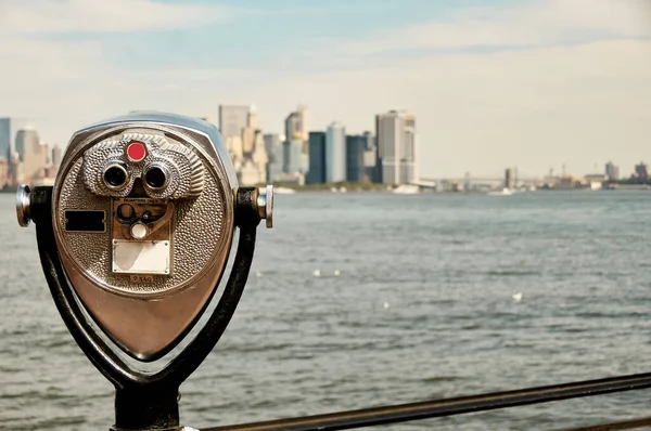 Manhattan silueti ve New York Limanı Özgürlük Adası 'ndan görüldü. Kule görüntüleme dürbünleri ön planda Manhattan silueti olan bir yüze benziyor.