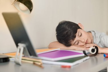 Stresli çocuk ödevini yapıyor. Çalışma masasındaki çocuk stres hareketleriyle ödev yapıyor. Stresli yüzüyle ev ödevi yapan tembel çocuk..