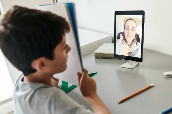 Evden online derslere katılan mutlu küçük çocuk. Karantina sırasında okul eğitimi ve sosyal uzaklık