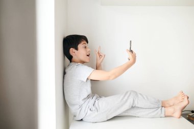 Sosyal ağlar için selfie çeken mutlu çocuk. Evdeki çocuk odasında.