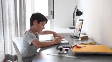 Evden online derslere katılan mutlu küçük çocuk. Karantina sırasında okul eğitimi ve sosyal uzaklık