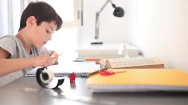 Stresli çocuk ödevini yapıyor. Çalışma masasındaki çocuk stres hareketleriyle ödev yapıyor. Stresli yüzüyle ev ödevi yapan tembel çocuk..