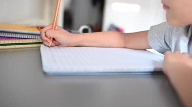 Not defterine yazan bir çocuk. Stresli çocuk ödevini yapıyor. Çalışma masasındaki çocuk stres hareketleriyle ödev yapıyor. Stresli yüzüyle ev ödevi yapan tembel çocuk..