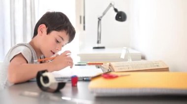 Stresli çocuk ödevini yapıyor. Çalışma masasındaki çocuk stres hareketleriyle ödev yapıyor. Stresli yüzüyle ev ödevi yapan tembel çocuk..