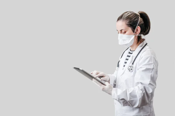 Doktor beyaz arka planda bir tablet tutuyor.