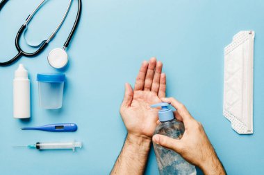 Doktorun ellerini hidroseksüel jel eldivenlerle dezenfekte ettiğini ve Coronavirüs salgınıyla mücadele etmek için gereken her şeyi maskelediğini görmek.