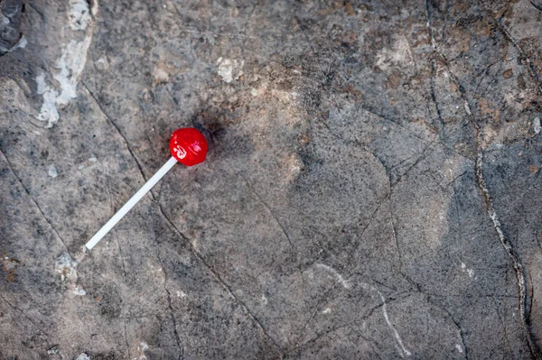 Czerwony lizak leżący na szorstkim betonowym tle — Zdjęcie stockowe