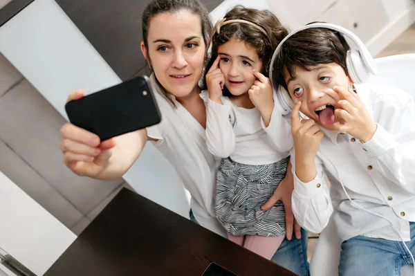 Kameraya poz veren bir grup insan. Olgun bir anne ve çocukları selfie çekiyor.