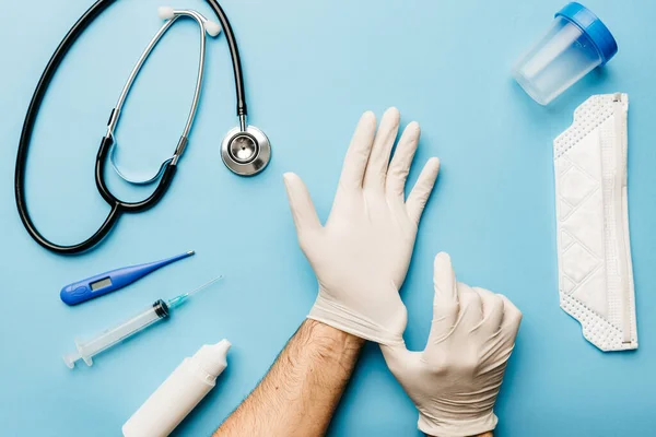 Eldivenleri ve maskeyi, koronavirüs salgınıyla mücadele için gerekli olan her şeyle uygun bir şekilde yerleştiren bir doktor görüntüsü.