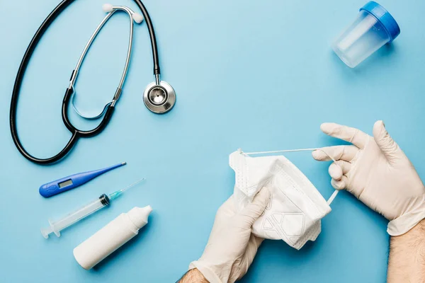 Eldivenleri ve maskeyi, koronavirüs salgınıyla mücadele için gerekli olan her şeyle uygun bir şekilde yerleştiren bir doktor görüntüsü.