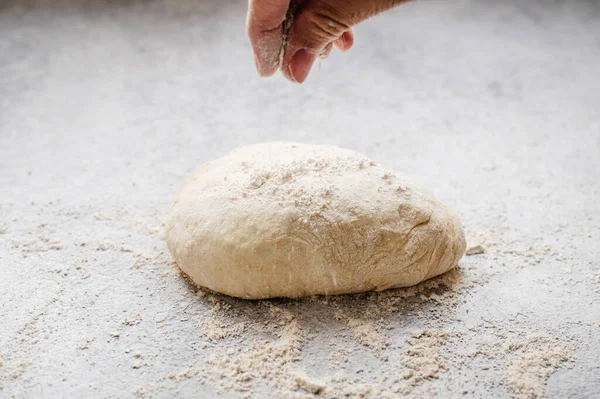 Mutfakta yapılan ev yapımı pizza hamuruna un ekliyorum.