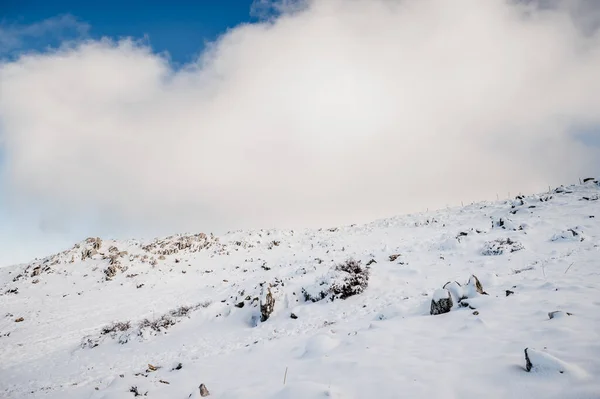 Detail of a mountain slope with heavy snowfall and a blue sky full of thick clouds in the background — Stock Photo, Image
