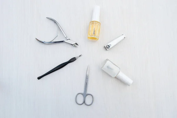 Metal manicure accessories and care products for nail and cuticle. Cuticle clippers, small cuticle scissors, nail clippers, cosmetic oil to soften the cuticle and a transparent firming nail Polish.