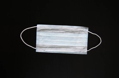 Koronavirüse karşı korunmak için antiviral tıbbi maske. Cerrahi koruyucu maske. Siyah arka planda tıbbi solunum bandajı var. Virüsün yayılmasını önlemek ve salgın COVID-19.