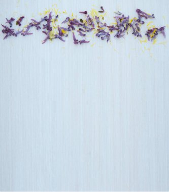 Boş bir yer ve beyaz ahşap arka planda sarı ve mor çiçek yaprakları olan bir kadın masaüstü düzeni. Boşluk. Stylize edilmiş stok fotoğrafı, web afişi. Düz yatış, üst görünüm.