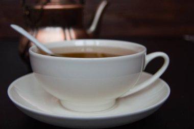 Siyah arka planda çay fincanı, çay tabağı ve kaşık.