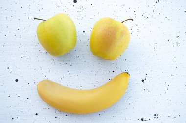 Emoji konsepti. Gülen meyve surat. Gözler için sarı elma ve beyaz arka planda bir gülümseme için sarı muz..